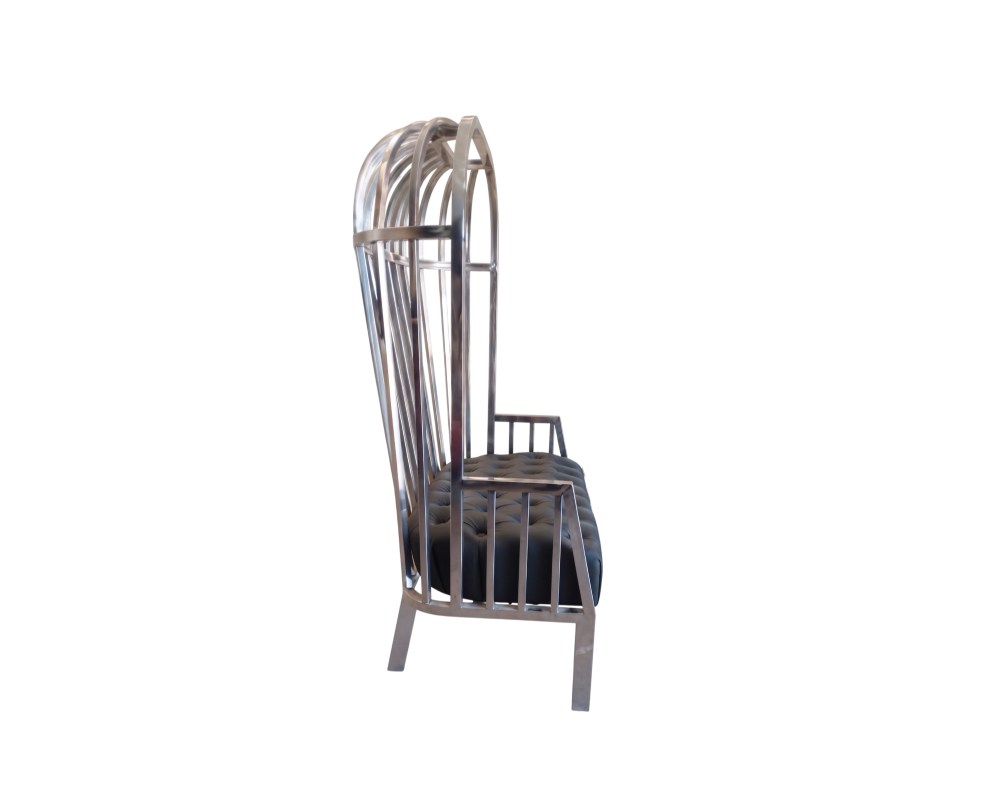 Se distingue por una estructura metálica alta que simula los barrotes de una jaula y un asiento tapizado en color oscuro con técnica de capitoné, combinando un estilo industrial con elegancia decorativa alquiler para eventos, publicidad, peliculas y series