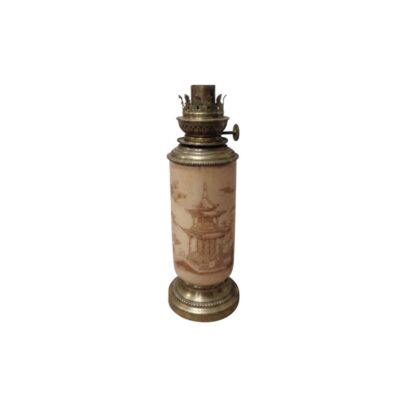 A table lamp with a cylindrical body in light colours, featuring delicate engravings or illustrations in a traditional Oriental style depicting pagodas and elements of nature, framed by a base and an upper burner mechanism; available for hire for events, advertising, films and TV series