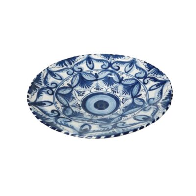 A decorative ceramic plate notable for its delicate hand-painted decoration in cobalt blue against a gleaming white background. Its design features a circular central motif surrounded by intricate, stylised plant and floral patterns that extend towards the rim, creating a symmetrical and balanced aesthetic. Available for hire for events, advertising, films and TV series.