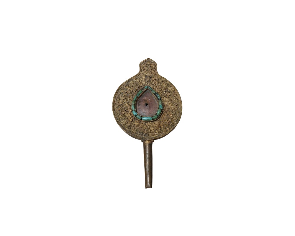 A metal object featuring an ornamental and traditional design, comprising a circular body with a slender upper extension, a cylindrical lower handle and a surface entirely engraved with raised plant motifs; available for hire for events, advertising, films and TV series