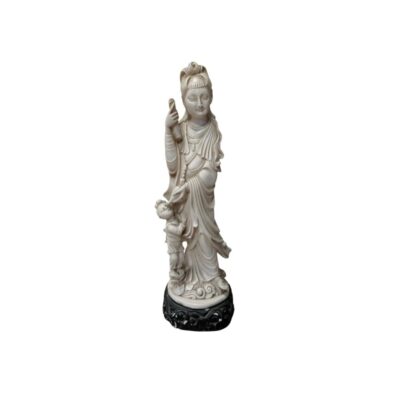 An ivory-coloured statuette depicting a traditional female figure in a draped tunic and elaborate headdress, accompanied by a small child figure at her side and mounted on a dark, carved base; available for hire for events, advertising, films and TV series