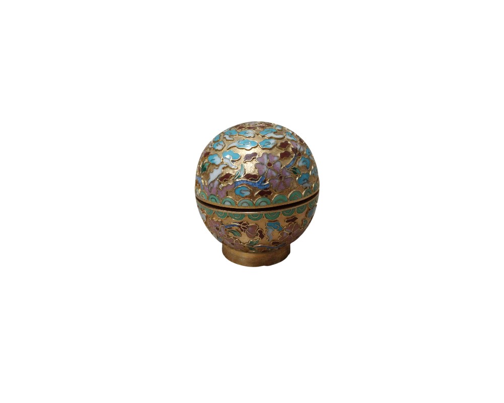 A small spherical box crafted using the cloisonné enamel technique, featuring an intricate decoration of floral and geometric motifs in various colours on a gilded metal frame. With its refined design and compact size, it serves as an ornamental collector’s item, ideal for storing small objects or as a decorative table centrepiece. Available for hire for events, advertising, films and TV series.