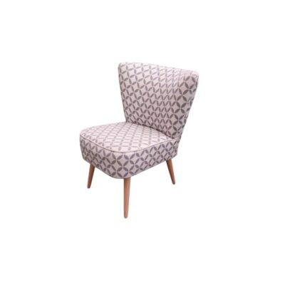 sillón butaca auxiliar de época, caracterizado por un cuerpo compacto y envolvente tapizado íntegramente en tejido textil con un distintivo patrón geométrico floral en tonos grises y blancos, sostenido sobre cuatro esbeltas patas cónicas de madera de soporte alquiler para eventos, publicidad, peliculas y series