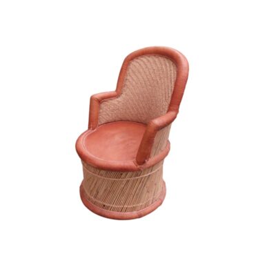 sillón de época fabricado con una estructura cilíndrica de mimbre y caña trenzada, provisto de un cómodo asiento, reposabrazos y remates perimetrales tapizados en auténtica piel en tonos marrones con costuras visibles alquiler para eventos, publicidad, peliculas y series