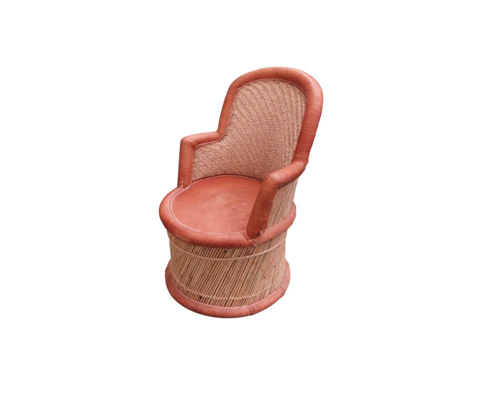 Vintage armchair featuring a cylindrical frame made of wicker and plaited cane, with a comfortable seat, armrests and edging upholstered in genuine leather in shades of brown with visible stitching. Available for hire for events, advertising, films and TV series.