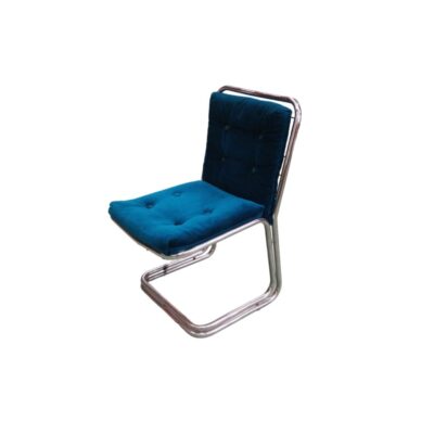 elegante silla auxiliar de diseño vanguardista, caracterizada por una estructura tubular metálica continua en voladizo (cantiléver) con acabado cromado y cojines acolchados con botones tapizados en suave tejido de terciopelo en tono azul profundo alquiler para eventos, publicidad, peliculas y series