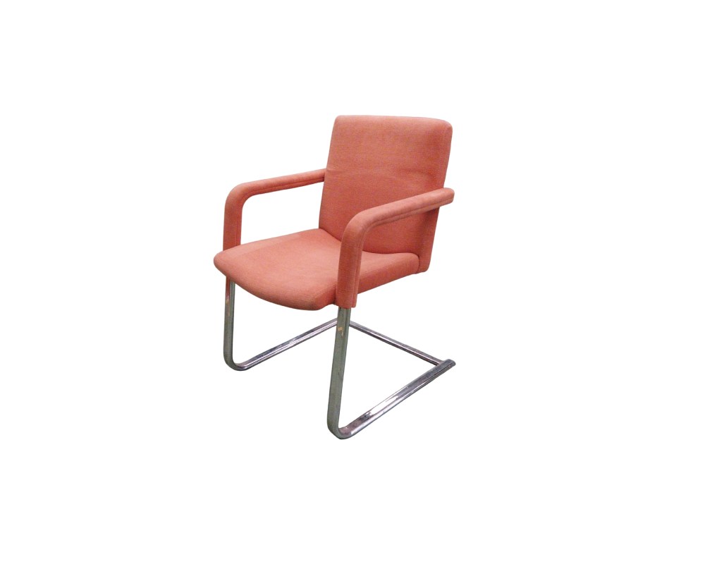 An elegant period chair with a modern design, characterised by a continuous cantilevered tubular metal frame with a chrome finish; the seat, backrest and armrests are upholstered in salmon-orange fabric. Available for hire for events, advertising, films and TV series.