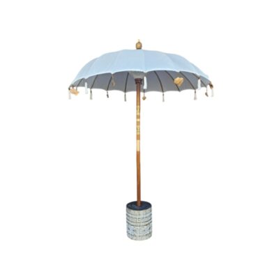 A white Balinese-style parasol, characterised by its handcrafted details and decorative gold-toned pendants and matching tassels along the edge; available for hire for events, advertising, films and TV series