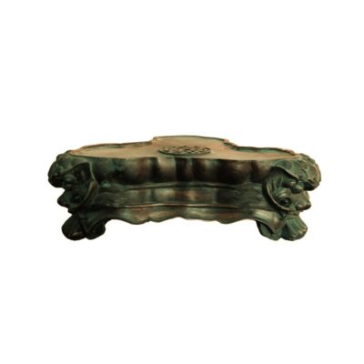 soporte decorativo bajo de metal, caracterizado por presentar una superficie superior lobulada con un detalle central grabado, un cuerpo con faldón curvado y esquinas esculpidas con relieves de cabezas de león alquiler para eventos, publicidad, peliculas y series