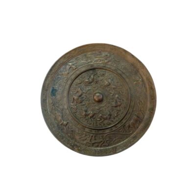An antique circular bronze mirror, characterised by its aged patina in dark tones and intricate relief ornamentation divided into several concentric circles. Available for hire for events, advertising, films and TV series.
