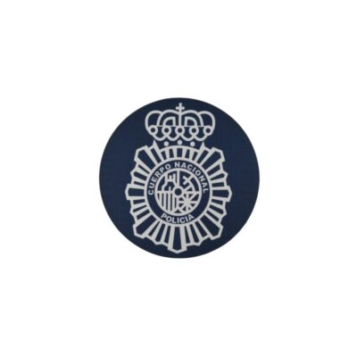 A circular fabric patch in dark blue, featuring the official emblem of the Spanish National Police Force embroidered or printed in light colours, comprising the eight-pointed star, the central coat of arms and the royal crown at the top. Available for hire for events, advertising, films and TV series.