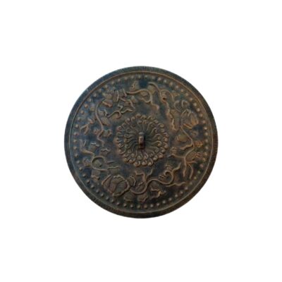 Circular metal mirror with a dark, distressed finish, featuring an intricate embossed design on its surface; available for hire for events, advertising, films and TV series