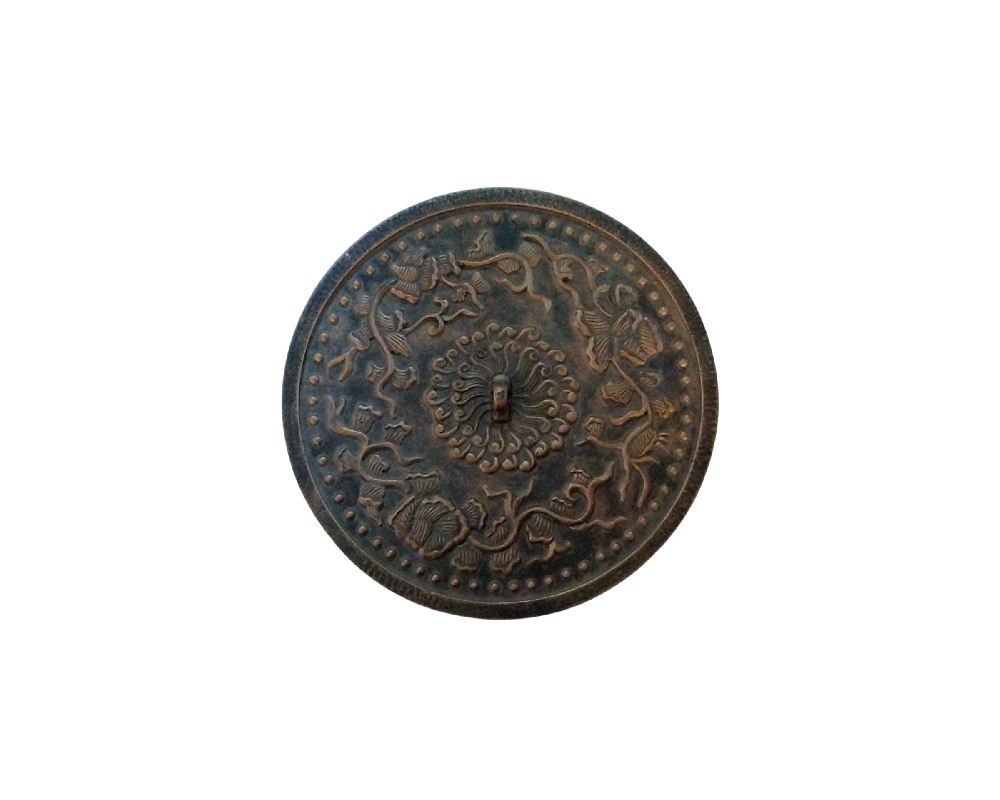 Circular metal mirror with a dark, distressed finish, featuring an intricate embossed design on its surface; available for hire for events, advertising, films and TV series