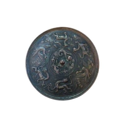 espejo circular de bronce con un acabado oscuro y envejecido, caracterizado por presentar un elaborado diseño en relieve en su superficie alquiler para eventos, publicidad, peliculas y series