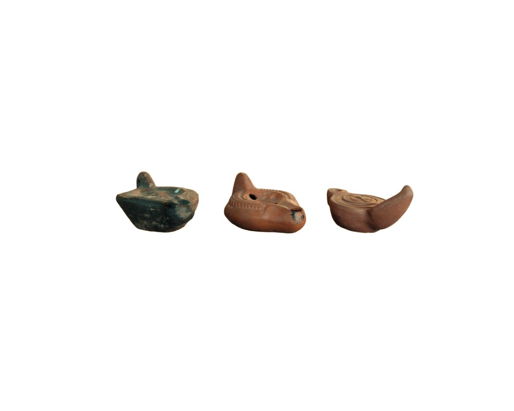 lote de tres pequeñas lámparas de aceite o lucernas de terracota de estilo clásico o romano, caracterizadas por sus cuerpos modelados en arcilla con orificios de llenado, pico quemador y asas traseras, presentando diferentes tonalidades y acabados envejecidos alquiler para eventos, publicidad, peliculas y series