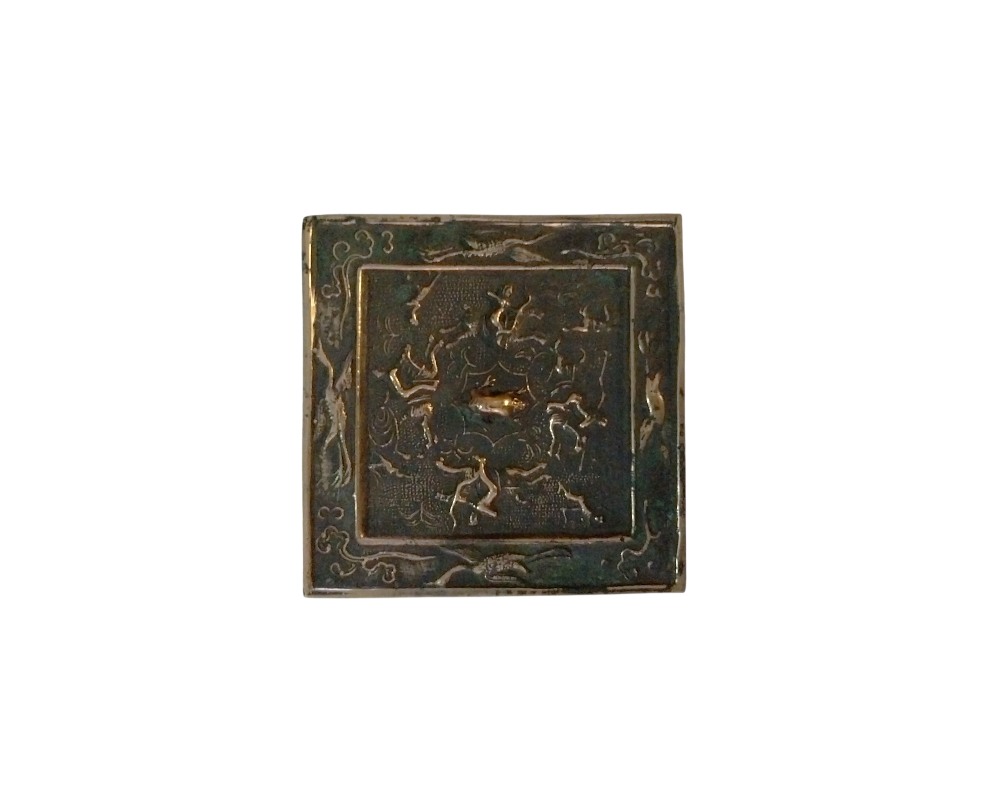 A square metal plaque in an antique style, characterised by a dark patina finish and intricate embossed ornamentation; available for hire for events, advertising, films and TV series