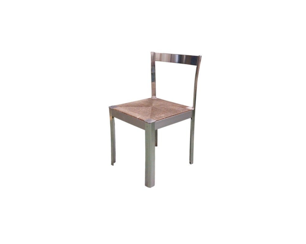 A modern vintage side chair, characterised by a metal frame with straight lines and a shiny chrome finish, and a handcrafted seat upholstered in wicker or natural fibre woven in a geometric pattern. Available for hire for events, advertising, films and TV series.