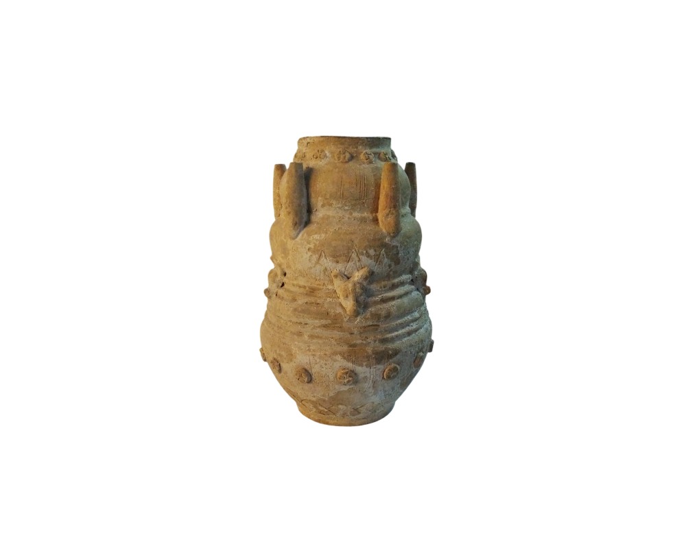 An antique-looking ceramic vessel in earthy tones, characterised by a robust design adorned with geometric reliefs, protrusions and decorative motifs distributed across its surface; available for hire for events, advertising, films and TV series