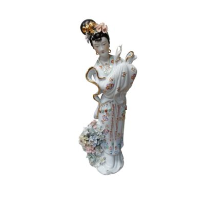 estatuilla de porcelana finamente detallada que representa a una figura femenina tradicional con un elaborado peinado decorado, vestimenta con motivos florales multicolores y bordes dorados, y un arreglo de flores en relieve a sus pies alquiler para eventos, publicidad, peliculas y series