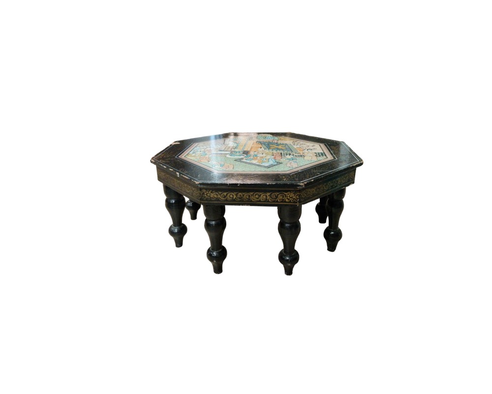 An octagonal coffee table with a dark-coloured finish, featuring a tabletop decorated with a traditionally styled painted scene surrounded by ornamental borders, and sturdy turned legs; available for hire for events, advertising, films and TV series