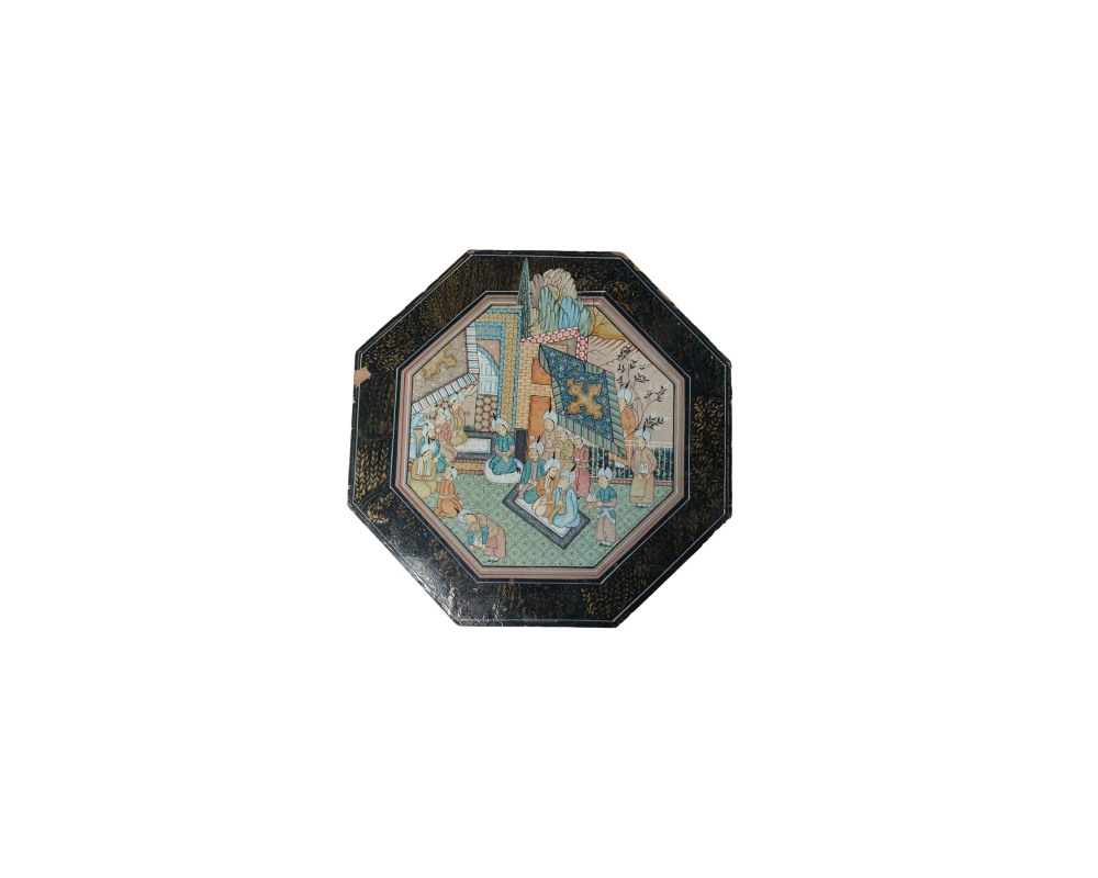 mesa baja de forma octagonal con acabado en tonos oscuros, caracterizada por una cubierta superior decorada con una escena pintada de estilo tradicional rodeada de cenefas ornamentales, y robustas patas torneadas alquiler para eventtos, publicidad, peliculas y series
