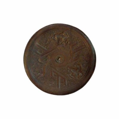 espejo circular de bronce antiguo con un acabado oscuro y envejecido, caracterizado por presentar una superficie ornamentada con un diseño simétrico en relieve que combina elementos geométricos angulares y figuras tradicionales distribuidas en torno a un botón central alquiler para eventos, publicidad, peliculas y series