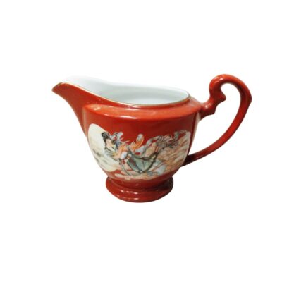 Ceramic milk jug with a pedestal base and a distinctive curved handle on top, characterised by a rich terracotta-coloured exterior glaze and a glossy white interior; available for hire for events, advertising, films and TV series