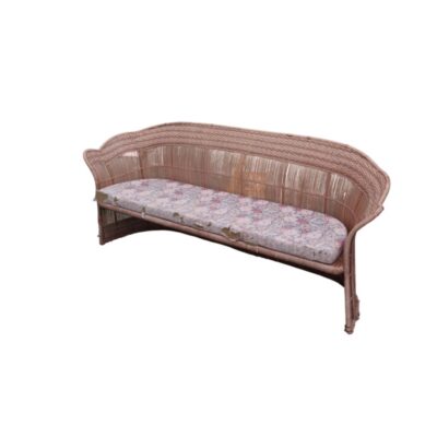 A spacious period sofa with a sturdy wicker frame and natural woven rattan, characterised by a curved, enveloping backrest with vertical rod panels and a long seat cushion upholstered in fabric with a classic floral print; available for hire for events, advertising, films and TV series