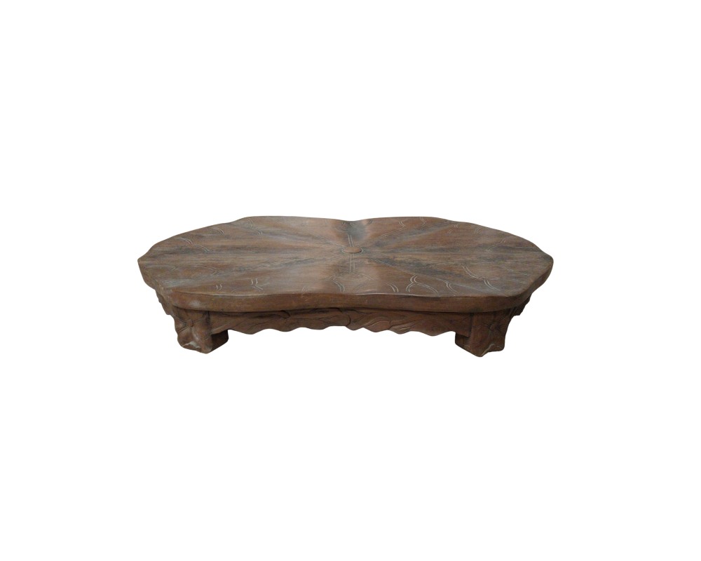 mesa baja de madera en tonos marrones y aspecto rústico, caracterizada por una superficie de forma orgánica y contornos irregulares que simulan una hoja, decorada con grabados radiales que representan las nervaduras centrales y un soporte inferior tallado alquiler para eventos, publicidad, peliculas y series
