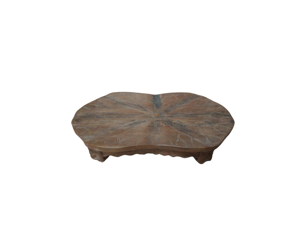 A low wooden table in shades of brown with a rustic finish, characterised by an organically shaped surface with irregular contours that resemble a leaf, decorated with radial carvings representing the central veins and a carved base – available for hire for events, advertising, films and TV series