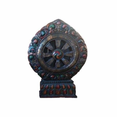 an ornate carving featuring, at its centre, a multi-spoked wheel (similar to a Dharma wheel) surrounded by an outer frame richly decorated with sinuous reliefs and traces of polychromy in aged shades of blue, reddish and greenish, which rests on a rectangular base decorated with lotus petal motifs. Hire for events, advertising, films and TV series