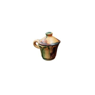Miniature pot with a side handle and matching lid, made of ceramic and decorated with handcrafted glaze in honey-coloured tones and greenish streaks with a dripped effect; available for hire for events, advertising, films and TV series