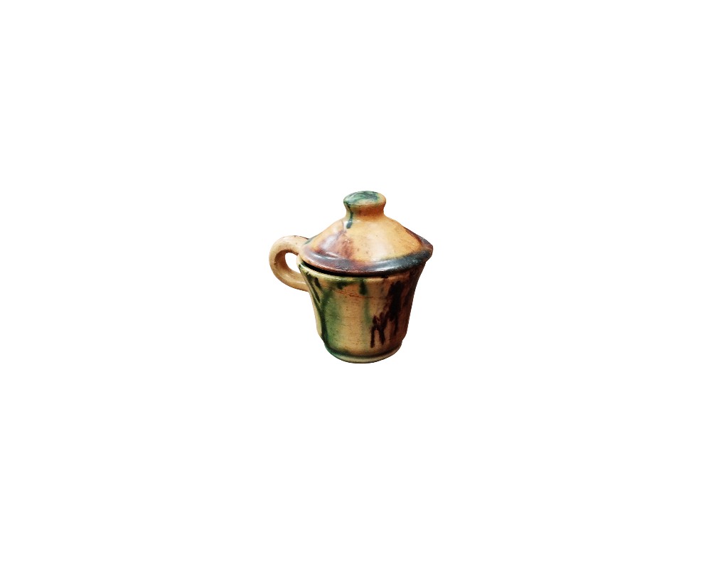 Miniature pot with a side handle and matching lid, made of ceramic and decorated with handcrafted glaze in honey-coloured tones and greenish streaks with a dripped effect; available for hire for events, advertising, films and TV series