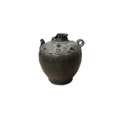 An antique ceramic vessel in dark shades with a rustic appearance, characterised by a sturdy globular body, a small ring-shaped handle on the side, a short spout and raised decorations on the upper part; available for hire for events, advertising, films and TV series
