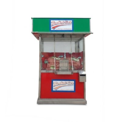 A modular commercial structure or kiosk-style sales booth, designed with a stainless steel frame, glazed panels and plinths in shades of red and green. It features integrated themed signage bearing the slogan ‘Rocket Car Drive-in Cinema & Restaurant – available for hire for events, advertising, films and TV series’.