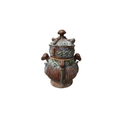 recipiente de cerámica tradicional de tonos terrosos y verdosos con acabado envejecido, caracterizado por un cuerpo acanalado en relieve, una tapa ajustada con pomo superior y detalles escultóricos tridimensionales, incluyendo pequeñas asas laterales y figuras zoomorfas integradas en su diseño alquiler para eventos, publicidad, peliculas y series