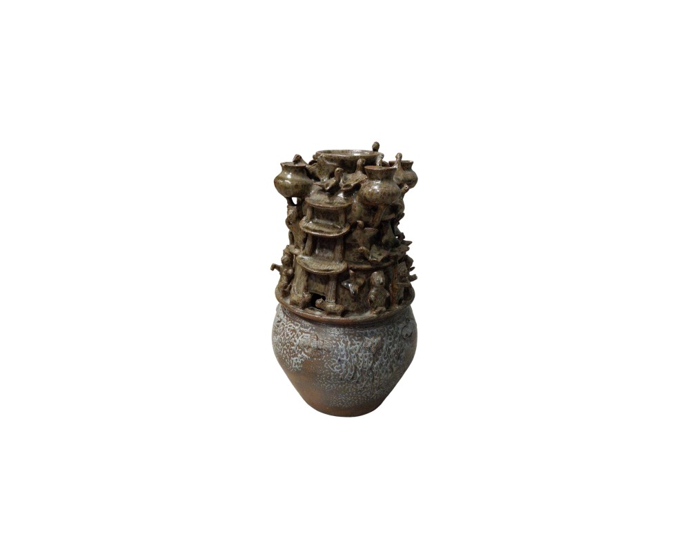 A traditional ceramic vessel in earthy and dark tones, characterised by a globular lower section with subtle textures and an elaborately decorated upper section crowned by dense sculptural figures depicting architectural structures, vessels and small figures; available for hire for events, advertising, films and TV series