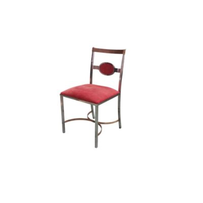 silla auxiliar de diseño vanguardista, caracterizada por una robusta estructura de soporte metálica con acabado cromado y refuerzos curvos inferiores, un asiento acolchado plano y un característico respaldo con placa ovalada central tapizados en tejido de terciopelo de color rojo vivo alquiler para eventos, publicidad, peliculas y series