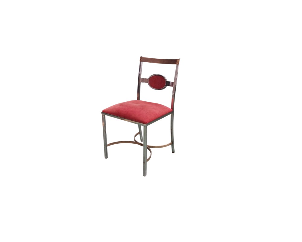 A contemporary-style side chair, characterised by a sturdy metal frame with a chrome finish and curved lower reinforcements, a flat padded seat and a distinctive backrest with a central oval panel, all upholstered in bright red velvet fabric. Available for hire for events, advertising, films and TV series.