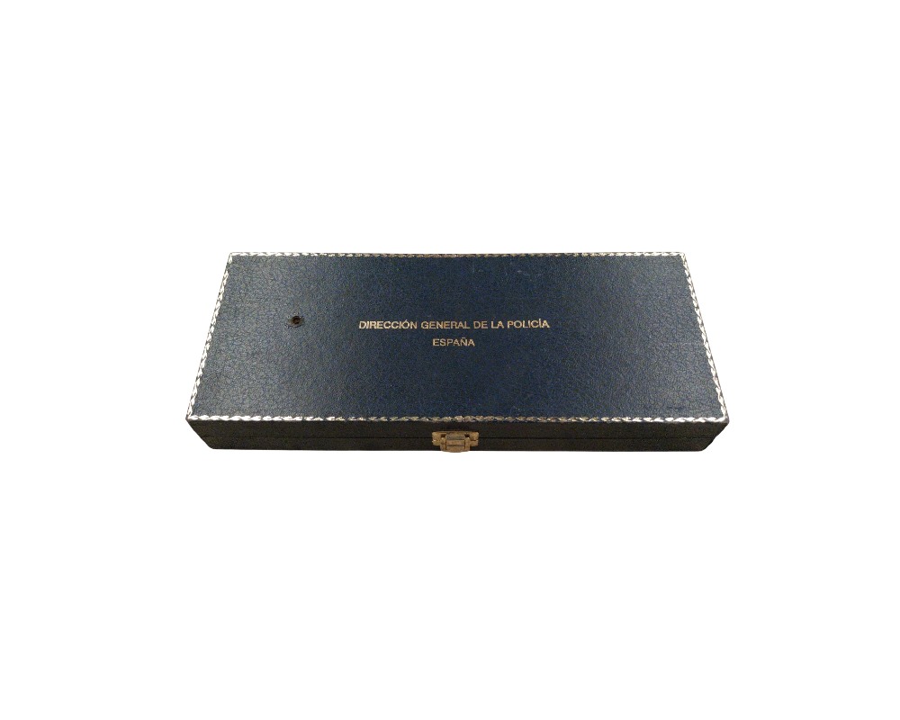 An elongated rectangular case in navy blue with a metal clasp, featuring the institutional text ‘DIRECCIÓN GENERAL DE LA POLICÍA ESPAÑA’ printed in gold on the lid and an ornate border; available for hire for events, advertising, films and TV series
