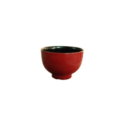 cuenco de cerámica de forma redondeada y base anular destacada, caracterizado por presentar un acabado esmaltado brillante de color rojo intenso en su exterior y un contraste oscuro en su interior alquiler para eventos, publicidad, peliculas y series