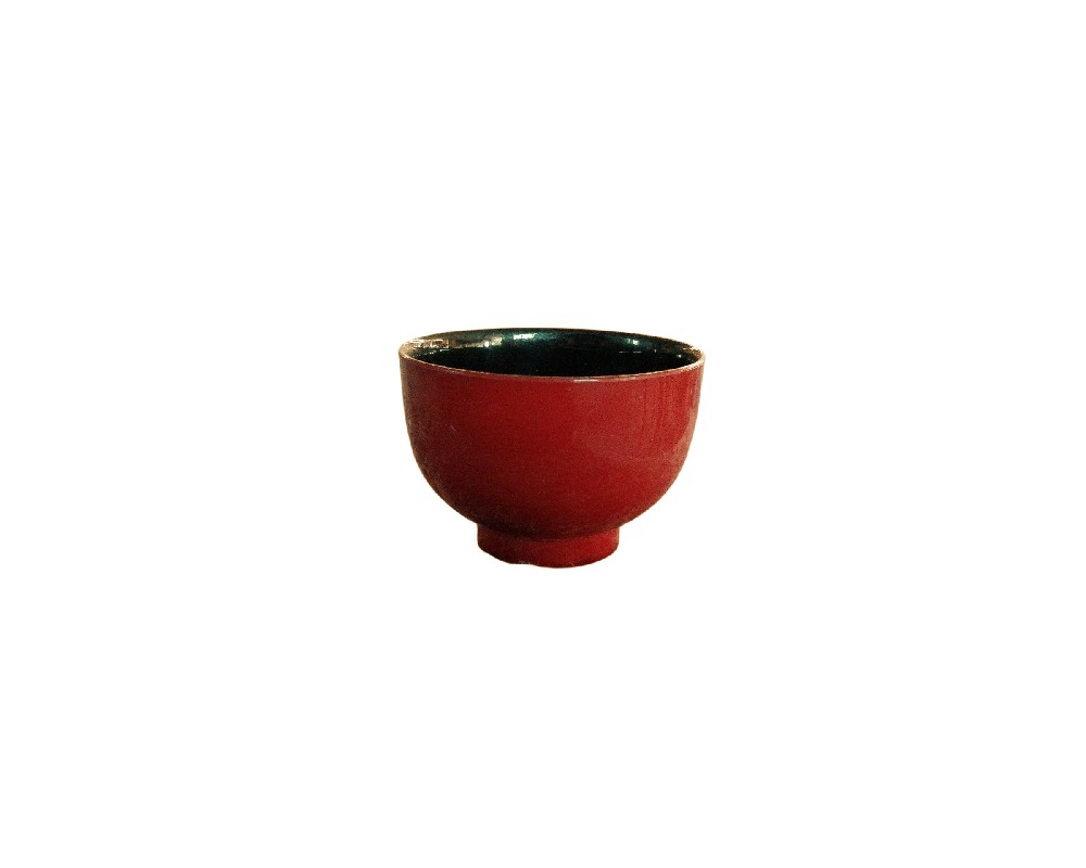 cuenco de cerámica de forma redondeada y base anular destacada, caracterizado por presentar un acabado esmaltado brillante de color rojo intenso en su exterior y un contraste oscuro en su interior alquiler para eventos, publicidad, peliculas y series