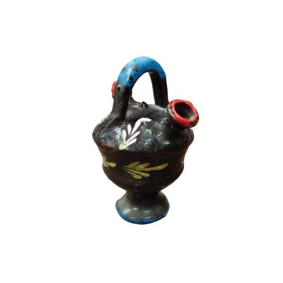 A ceramic jug with a flared base, a dark-coloured bulbous body, an arched handle at the top in shades of blue and black, and a spout with a red rim, all hand-decorated with simplified floral and plant motifs; available for hire for events, advertising, films and TV series