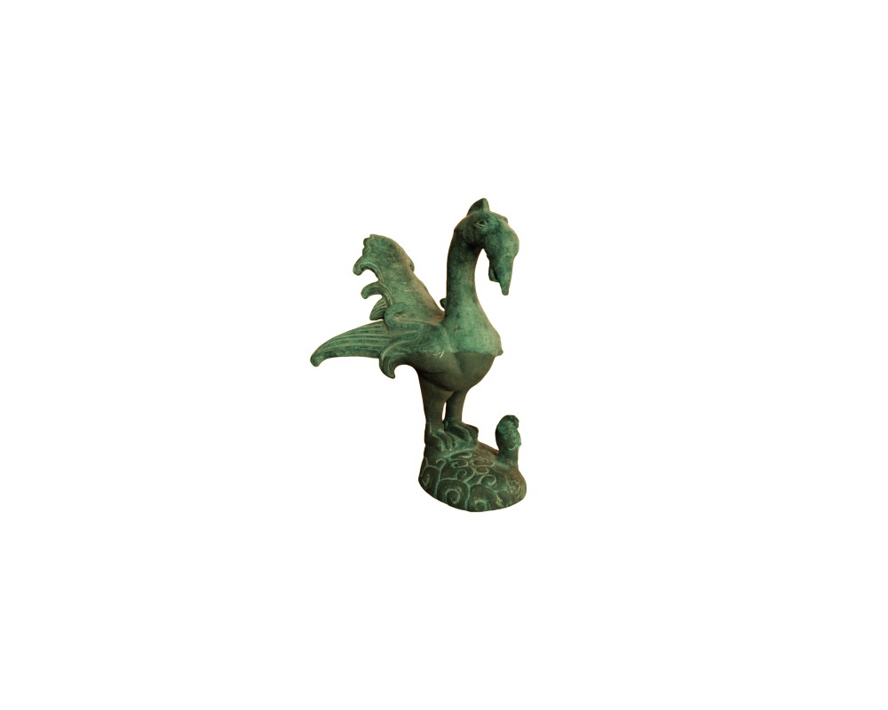 figura ornamental de metal con acabado de pátina verde envejecida, caracterizada por representar a un ave estilizada de tipo mitológico o fénix con el plumaje detallado, cola abierta y posada sobre una base decorada que incluye una pequeña figura secundaria alquiler para eventos, publicidad, peliculas y series
