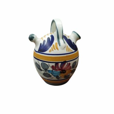 A small traditional ceramic water jug with a bulbous body, a vertical handle at the top, a spout and a rim, hand-decorated with striking floral motifs and stripes in shades of blue, yellow and red on a light glazed background; available for hire for events, advertising, films and TV series