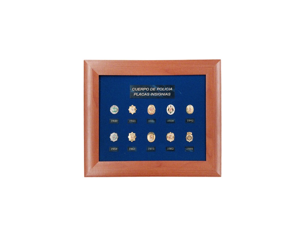 cuadro de presentación con marco de madera y fondo de terciopelo azul, diseñado para exhibir una colección de diez miniaturas de placas e insignias históricas del Cuerpo de Policía, ordenadas cronológicamente con sus respectivos años desde 1920 hasta 1989 y una placa identificativa superior que reza "CUERPO DE POLICIA PLACAS INSIGNIAS" alquiler para eventos publicidad, peliculas y series