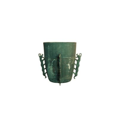 recipiente de metal de aspecto antiguo, caracterizado por presentar una pátina verde envejecida, relieves decorativos de estilo tradicional en su cuerpo, caracteres incisos en la parte superior y dos asas laterales con forma zoomorfa alquiler para eventos, publicidad, peliculas y series