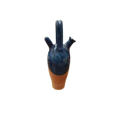 A slender, elongated water jug, characterised by an upper section with a striking glossy cobalt blue glazed finish, which contrasts elegantly with its natural, unglazed terracotta base. Available for hire for events, advertising, films and TV series.