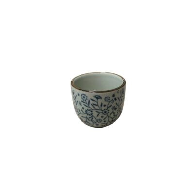 A small glass with a slightly domed cylindrical body, characterised by a finely contoured rim and a white glaze decorated with a dense pattern of floral motifs and intertwined stems in shades of cobalt blue; available for hire for events, advertising, films and TV series