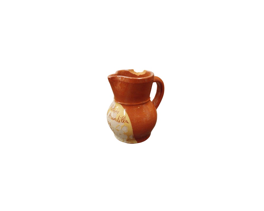 A small ceramic jug with a bulbous body, a side handle and a spout, characterised by a glossy terracotta-coloured glaze and a front panel bearing a handwritten inscription reading ‘Molino Arandilla’ – available for hire for events, advertising, films and TV series